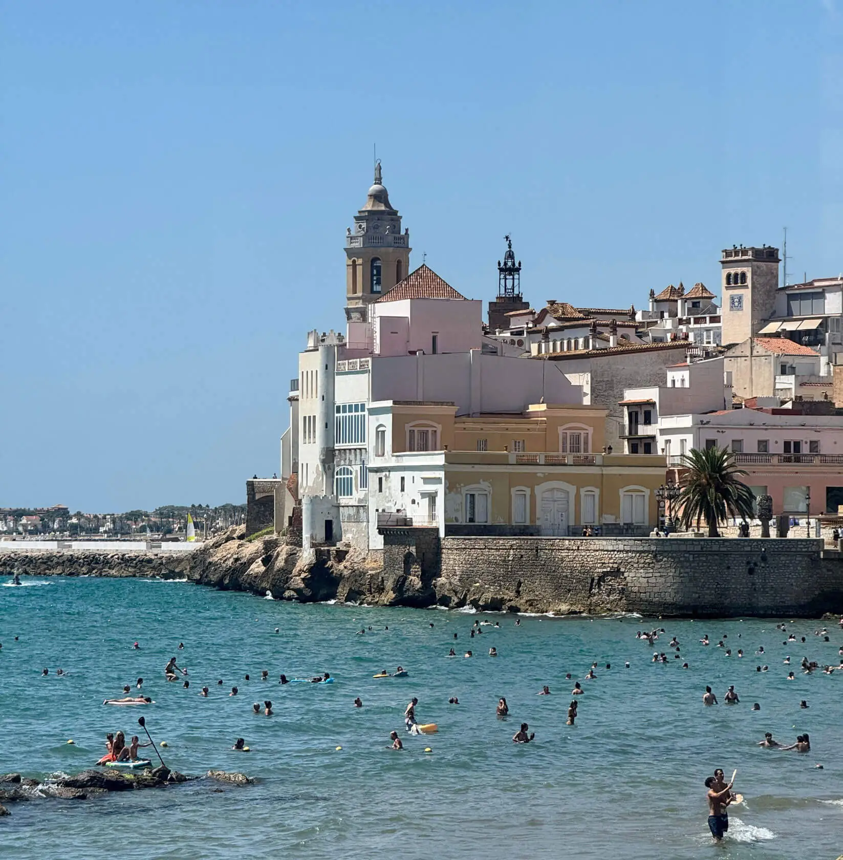 Bassa Rodona gay beach in Sitges with Mediterranean seafront and beachgoers.